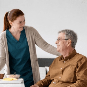 Healthcare worker smiling with an elderly man at a dining table in a residential care setting