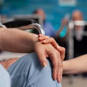 Support worker holding the hand of a person in a wheelchair, providing compassionate support for DVA services